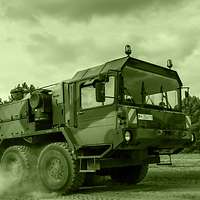 Unter großer Staubentwicklung transportiert ein Schwerlasttransporter einen Transportpanzer Fuchs.