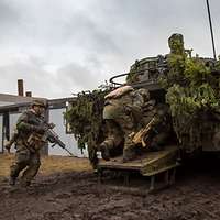 Drei Soldaten klettern durch die geöffnete Heckklappe eines getarnten Schützenpanzers Puma.
