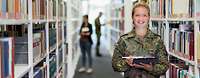 Eine Soldatin posiert für Bildung und Forschung in der Bundeswehr Eine Soldatin steht mit einem Tablet in der Hand in einer Bibliothek