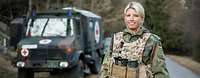 Eine Soldatin steht mit Schutzweste vor einem Krankentransportwagen der Bundeswehr