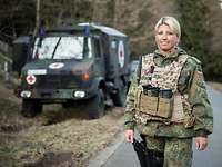 Der Sanitätsdienst der Bundeswehr benötigt eine starke Reserve Eine Soldatin steht mit Schutzweste vor einem Krankentransportwagen der Bundeswehr