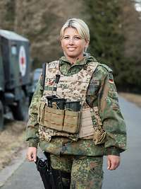 Der Sanitätsdienst der Bundeswehr benötigt eine starke Reserve Eine Soldatin steht mit Schutzweste vor einem Krankentransportwagen der Bundeswehr