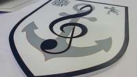 Im Wappen des Marinemusikkorps schlängelt sich ein Notenschlüssel um einen Anker