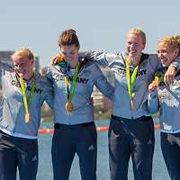 Vier Frauen in Sportanzügen mit Goldmedaillen um den Hals.
