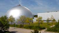 Halbkugelförmiger Zielsimulationsdom der WTD 81 in Greding mit Bäumen und einer Wiese im Vordergrund
