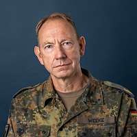 Ein Soldat im Feldanzug chaut lächelnd in die Kamera.