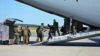 Soldaten bilden auf der Ladeklappe eines A400M eine Kette und laden Gepäck in einen Transportwagen.