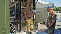 Ein Soldat steht vor der Feldwäscherei und erklärt die Abläufe Generalarzt Dr. Most