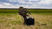 Soldat mit Rucksack steigt über Hindernis