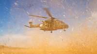 Ein Hubschrauber der Bundeswehr fliegt knapp über dem Boden und wirbelt dabei viel Staub auf.