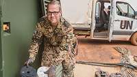 Ein Soldat hält einen alten und einen neuen Ölfilter in den Händen