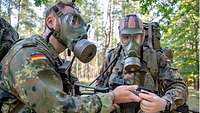 Zwei Soldaten mit Schutzmaken stellen sich den Kompass ein.