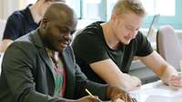 Zwei Studenten sitzen an einem Tisch und arbeiten