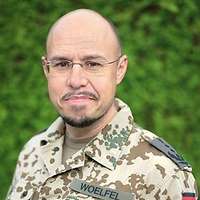 Ein Mann mit Glatze und Ziegenbart, randlose Brille