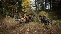 Zwei getarnte Soldaten mit Gewehren in Stellung im Wald