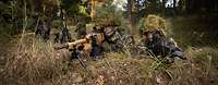 Soldaten mit Gewehren in Stellung Zwei getarnte Soldaten mit Gewehren in Stellung im Wald