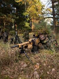 Soldaten mit Gewehren in Stellung Zwei getarnte Soldaten mit Gewehren in Stellung im Wald