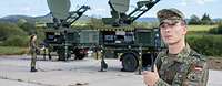 Ein Soldat steht vor einer Satellitenanlage der Bundeswehr