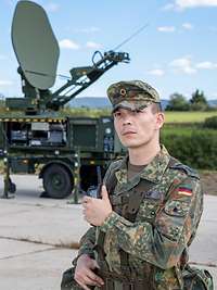 Soldaten des IT Bataillon 281 in Gerolstein vor einer SatCom Bodenstation Ein Soldat steht vor einer Satellitenanlage der Bundeswehr