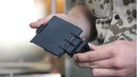 Ein Soldat hält ein mit dem 3D-Drucker gedrucktes Teil in den Händen 