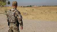 Fabio L. steht vor einem Feld und blickt in die Ferne