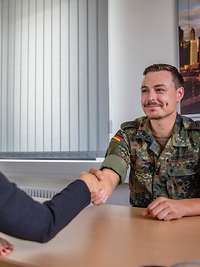 Ein Reservist sitzt Hände schüttelnt am Tisch 