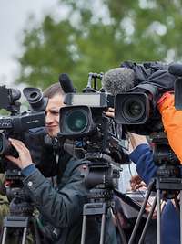Journalisten bei der Arbeit Journalisten stehen mit ihren Kameras und ihren Stativen nebeneinander. Alle Objektive schauen in eine Richtung.