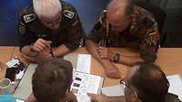 Vier Soldaten sitzen an einem Tisch, Aufnahme von oben.