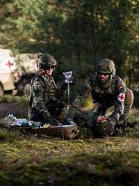 Sanitätsdienst der Bundeswehr Zwei Sanitäter versorgen einen am Boden liegenden Verwundeten