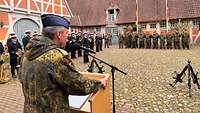Ein Soldat vor einer Gruppe angetretener Soldaten und Musiker der Bundeswehr