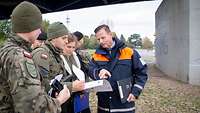 Soldaten und ein Mann in Schutzjacke im Gespräc