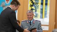 Ein Soldat übergibt ein Wappen an einen Zivilisten.