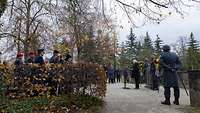 Zivile und militärische Gäste lauschen der Ansprache auf dem Friedhof.