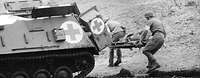 Soldaten des Sanitätsdienstes bei einer Übung mit dem Panzer Hotchkiss Schwarzweiß-Aufnahme: Zwei Soldaten laufen mit einem Verletzten auf einer Trage zum Sanitätspanzer Hotchkiss.