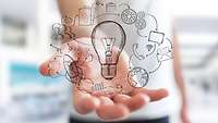 Businessman holding hand drawn lightbulb and multimedia icons