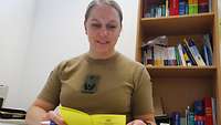 Oberstabsarzt Nadine A. sitzt in ihrem Büro und hält einen Impfpass in ihren Händen