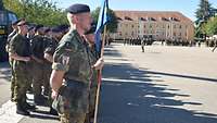Soldaten sind auf einem Exerzierplatz bei Sonnenschein in Formationen angetreten.