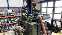 Soldaten der Bundeswehr, darunter auch ein Sachverständiger, statten einen Bundeswehr-Lastwagen mit Gerät und Material aus.