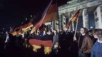 Vom Mauerfall zur Wiedervereinigung Viele Menschen mit Deutschland-Flaggen am Brandenburger Tor