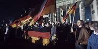 Menschen am Brandenburger Tor feiern den Fall der Berliner Mauer Viele Menschen mit Deutschland-Flaggen am Brandenburger Tor