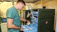 Ein Pfleger prüft an einem Medikamentenschrank eine Medikamentenpackung