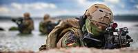 Aktuelles aus der Marine Zwei Soldaten in Flecktarnuniform und Kampfhelmen mit Sturmgewehren im Anschlag, im Hintergrund eines Meeresbucht.