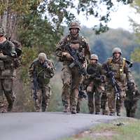 Soldaten marschieren auf einer Landstraße.