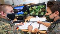 Zwei Soldaten mit Mund-Nasen-Schutz besprechen sich.