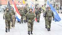 Soldaten marschieren mit Fahnen in der Hand 