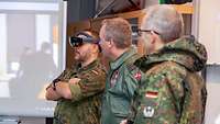 Drei Soldaten stehen nebeneinander, während einer davon eine Virtual-Reality-Brille trägt.