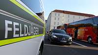 Ein Dienstfahrzeug der Bundeswehr und ein Bus. Davor ein Fahrzeug der Feldjäger.