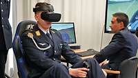 Der Offiziersanwärter sitzt im VR-Simulator. Auf den Monitoren können seine Bewegungen verfolgt werden