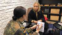 Zwei Junge Frauen sitzend im Gesräh. Eine ist in zivil, eine in Uniform