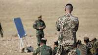 Nachdem die irakischen Soldaten knapp vier Monate die Schüler waren, dürfen Sie nun allein ausbilden Ein deutscher Soldat schaut einem irakischen Soldaten bei der Ausbildung zu